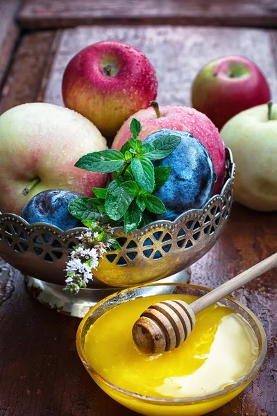 Apples and plums in iron vase