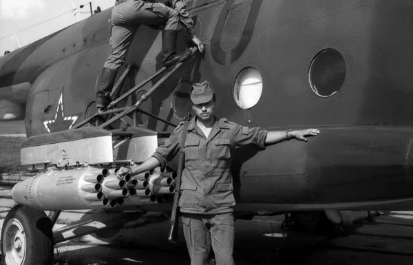 A soldier stands near a combat helicopter Mi-8. Film scan. Large grain