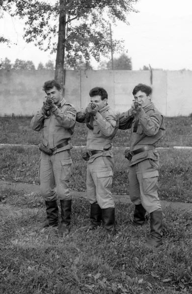 Soldiers posing with guns. Preparations for shooting. Film scan. Large grain