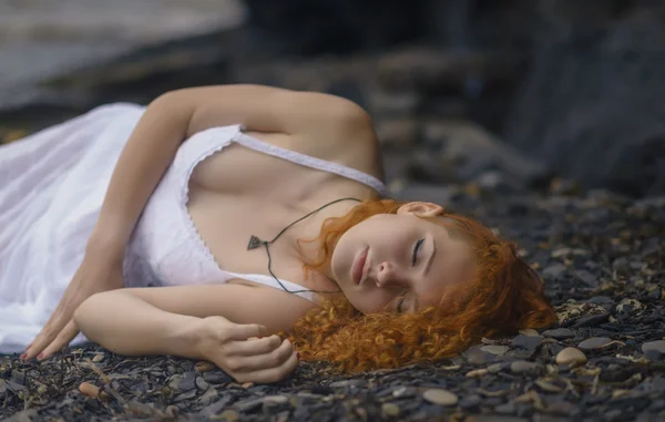 Beautiful redhead woman at the rocky beach.