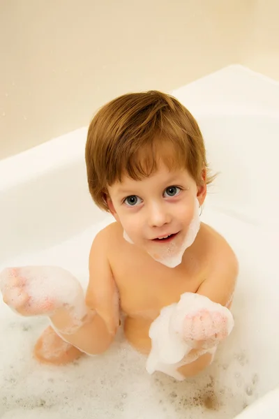 Cute boy taking a bath with foam