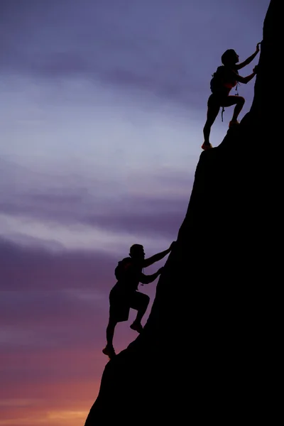 Silhouette man and woman backpackers climb up