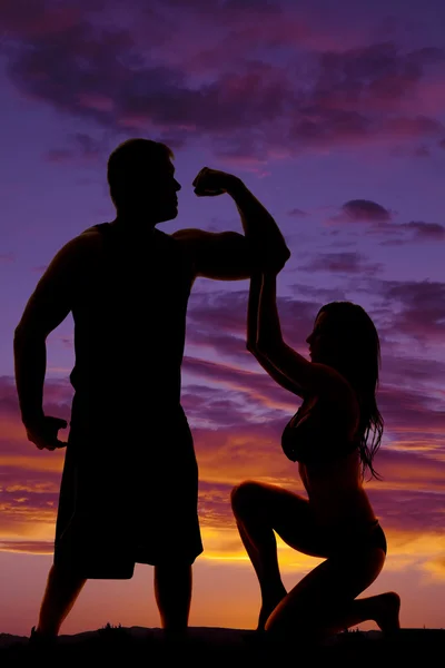 Silhouette of woman in bikini reach up with both hands with stro