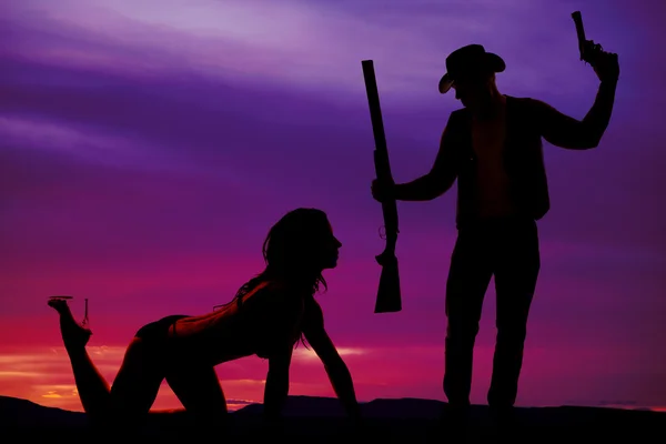 Silhouette of sexy woman crawling with cowboy and guns