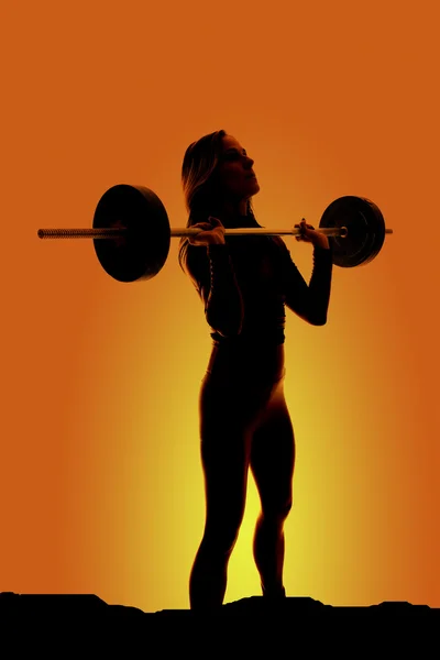 Silhouette of fit woman barbell by chest