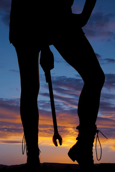 Silhouette woman legs holding wrench