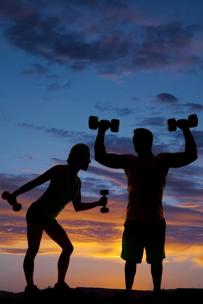 Silhouette of man and woman lifting weights