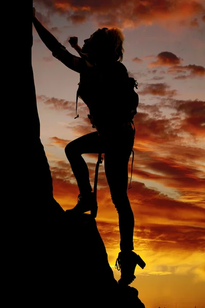 Silhouette of woman climbing mountain