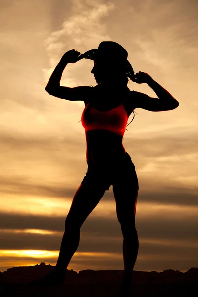 Silhouette of cowgirl stand look side hands on hat