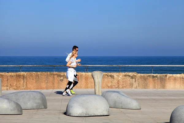 People run on promenade in Tel Aviv port, Israel.