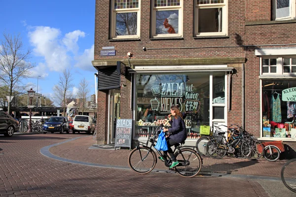 Local woman on bicycle in historical center in Amsterdam, Nether
