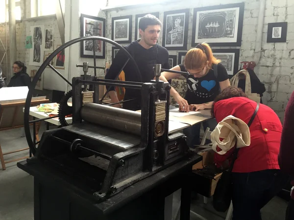 People work on old printing machine on craft workshop