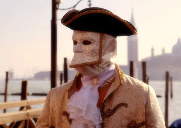 Masked person in costume on pier in St. Mark's Square during the