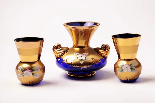 Empty blue and gold ornate glass vase and small wineglass