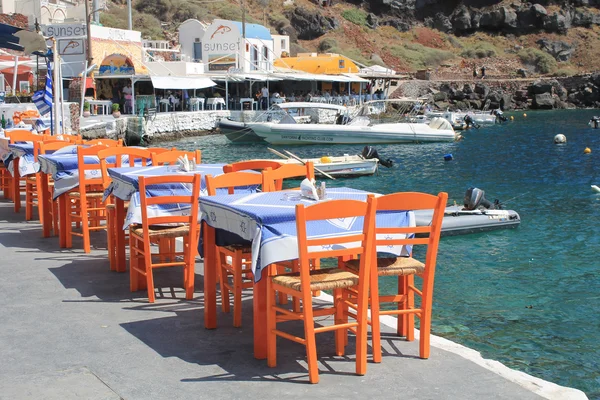 Greek tavern with orange wooden chairs by the sea coast, Greece,