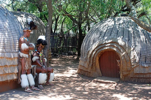 Zulu men wearing warrior dress near tribal straw house, South Africa