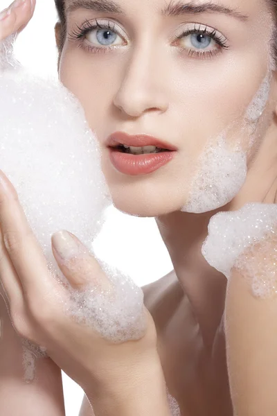 Beautiful woman cleaning her face with a foam treatment