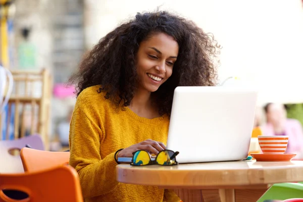 Happy african woman using laptop at cafe