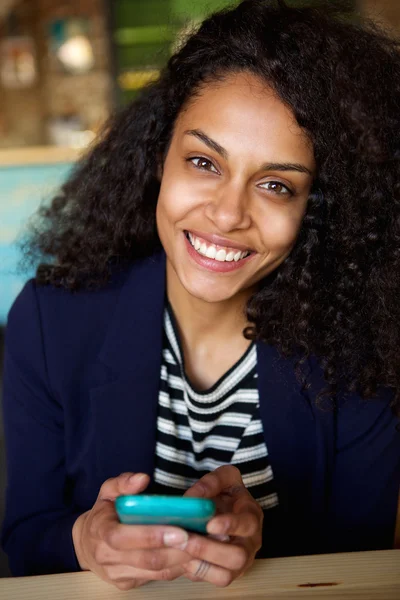 Smiling woman sitting at a cafe table with cellphone