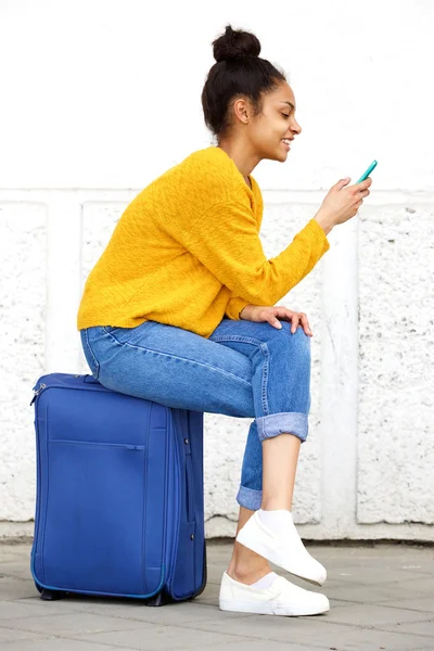 Relaxed female traveler sitting on suitcase