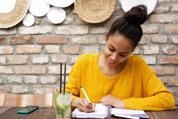 Beautiful young black woman writing notes