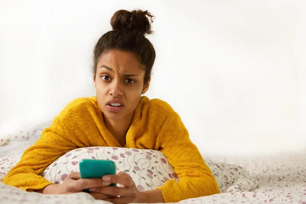 Young woman with confused face expression sitting in bed