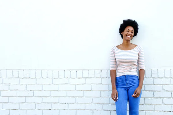 Confident happy woman standing by white wall