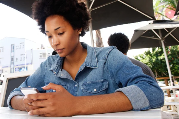 Young woman sitting and using cell phone outside