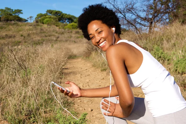 Woman runner outside in field with mobile phone