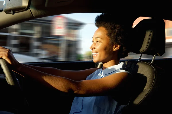 Happy young african woman driving a car