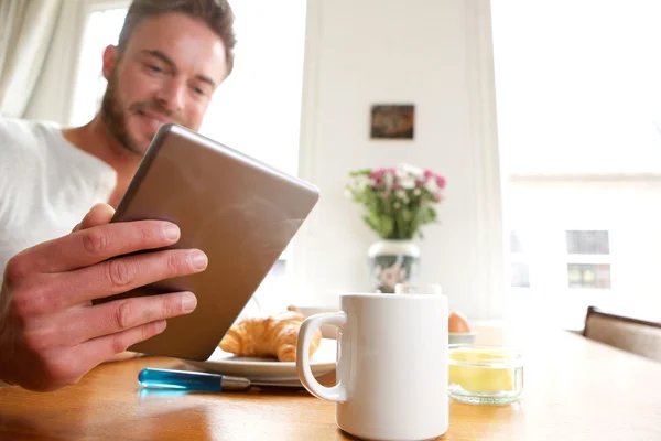 Happy man with breakfast holding tablet