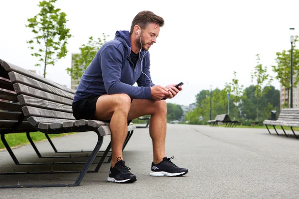 Older athlete sitting listening to music outside