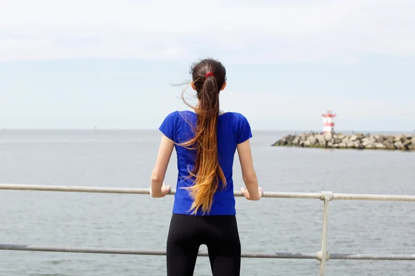 Sporty woman from behind by the sea