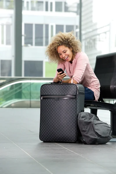 Woman waiting with suitcase and phone