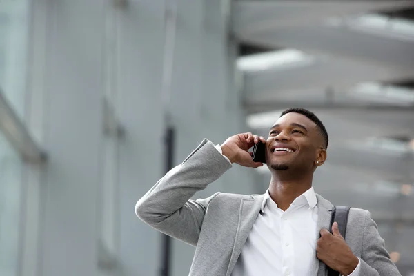 Happy young man talking on mobile phone inside building