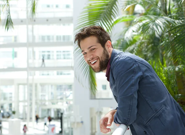 Happy man leaning inside bright building
