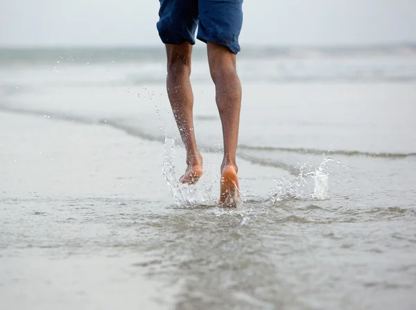 Running with bare feet in water by the beach