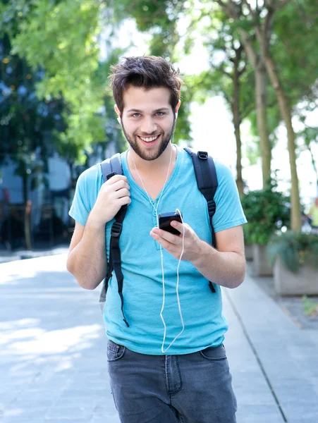 Young man walking outdoors with mobile phone