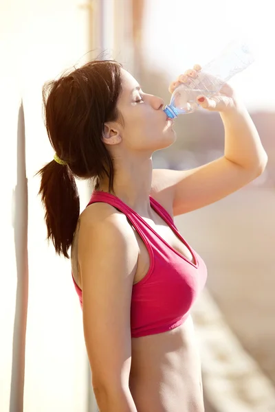 Healthy young woman drinking water from bottle
