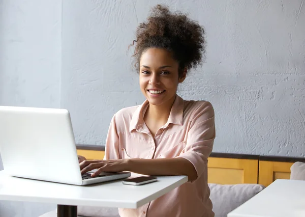 Smiling young black woman working on laptop