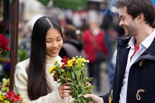 Young man giving flowers to beautiful woman