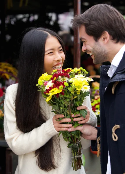 Happy man giving flowers to smiling woman