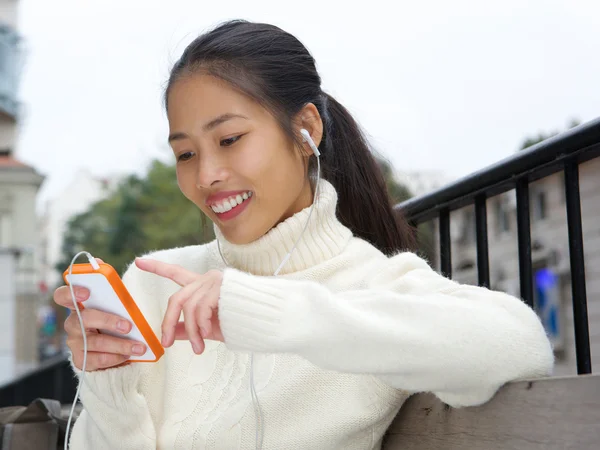 Young asian woman smiling with cellphone and earphones