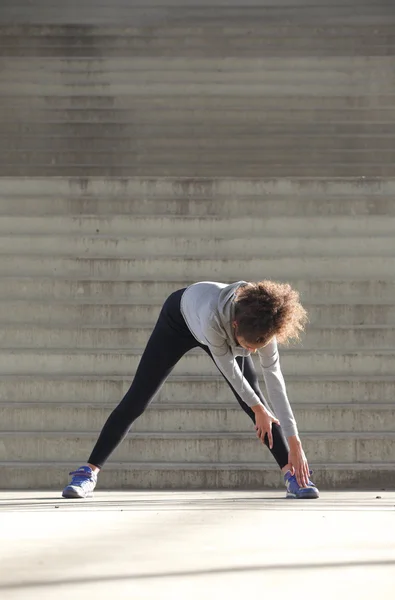 Young woman bending down stretching leg muscles