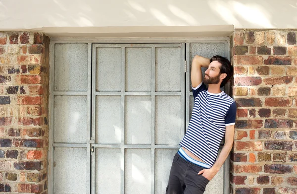 Male fashion model leaning against wall outdoors