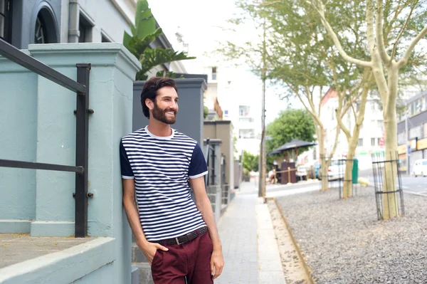 Relaxed smiling man leaning on wall outdoors