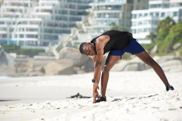 Man stretching leg muscles at the beach