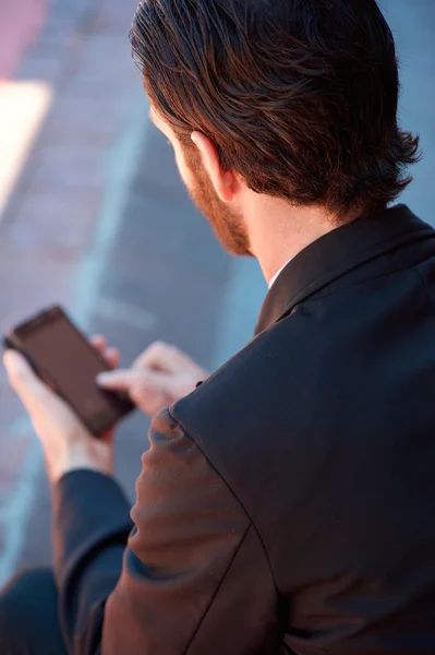 Young businessman holding mobile phone from behind