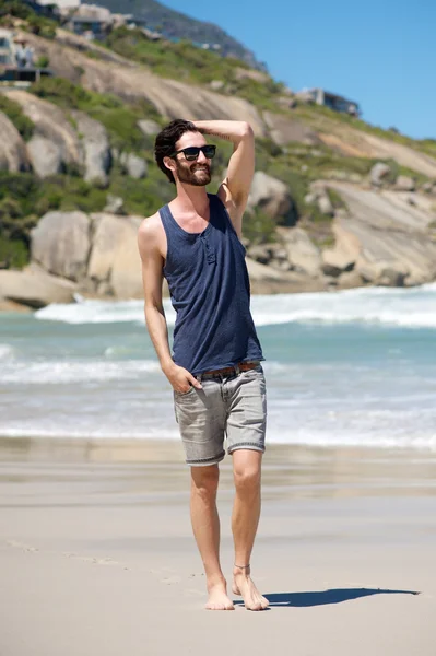 Happy young man on vacation walking barefoot on beach