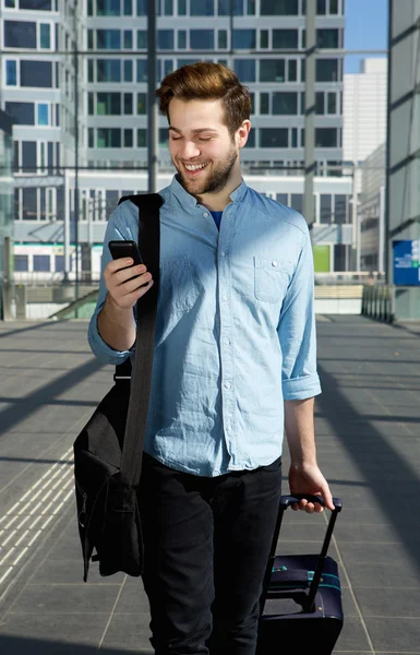 Young man walking at airport with bags and mobile phone